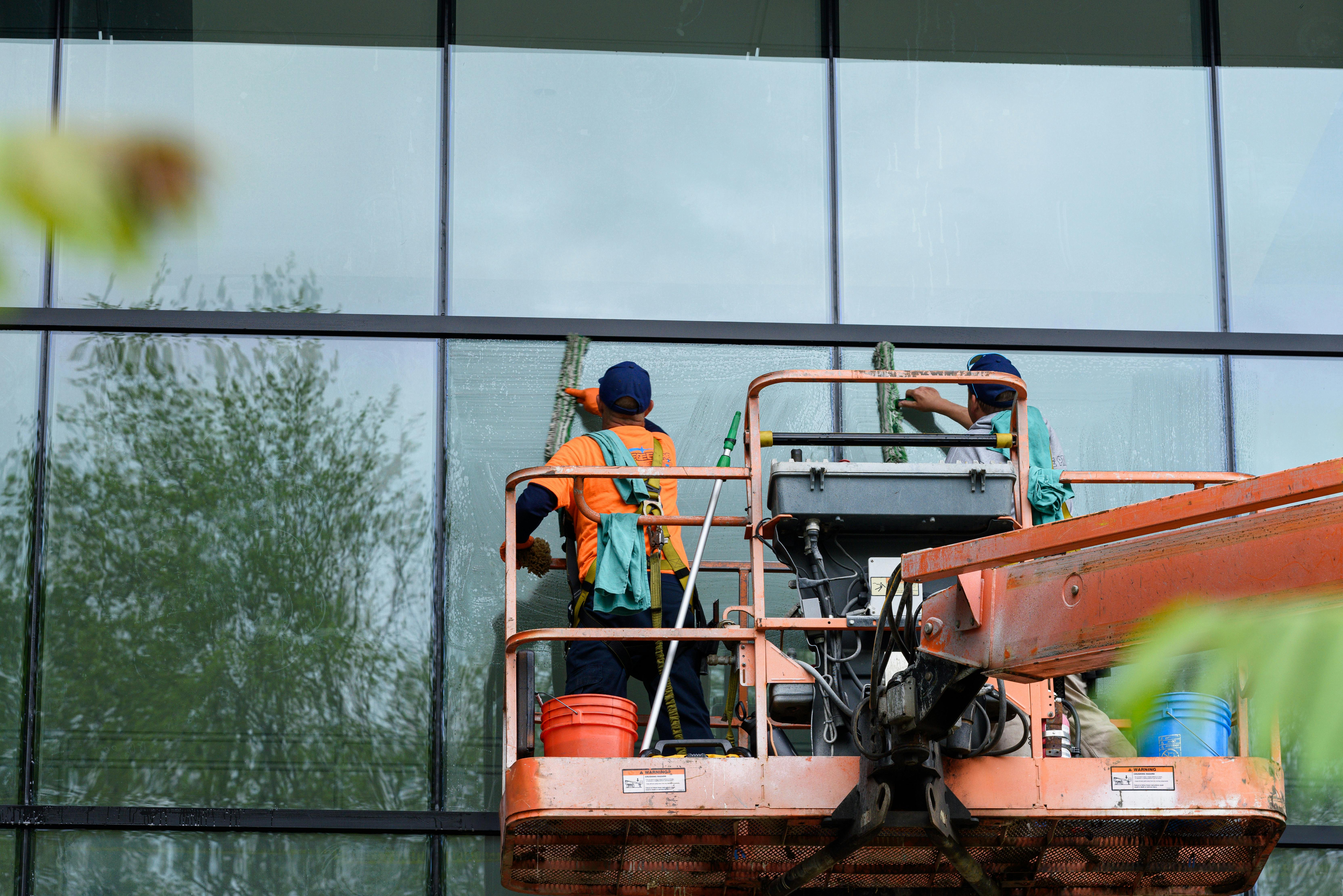 Commercial window cleaning team on lift platform servicing building in Utah